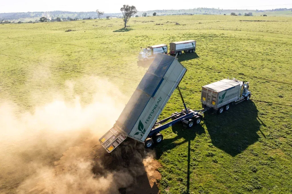 Side-tipper truck delivering bulk fertiliser in a paddock